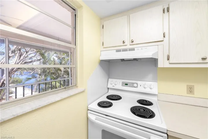 Kitchen featuring white electric stove, a wealth of natural light, and under cabinet range hood