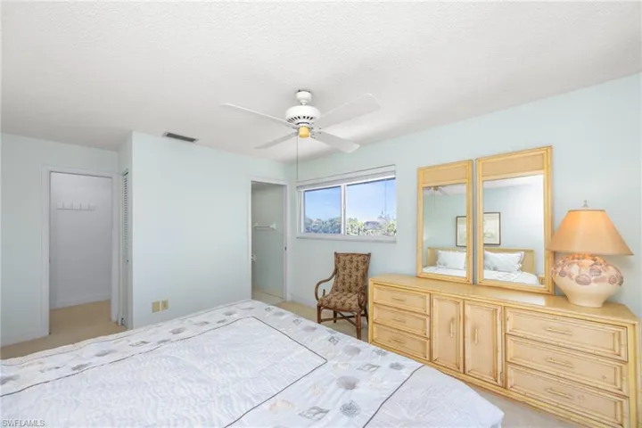Bedroom featuring ceiling fan, light carpet, a textured ceiling, and visible vents
