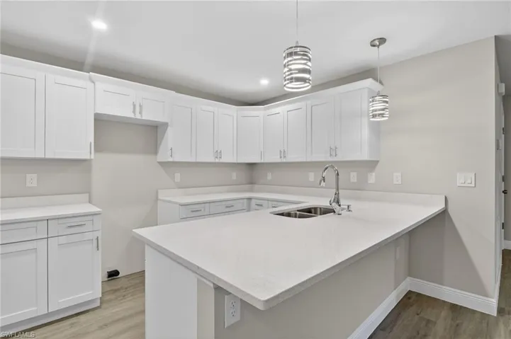 Kitchen featuring white cabinets, decorative light fixtures, and light wood-style flooring