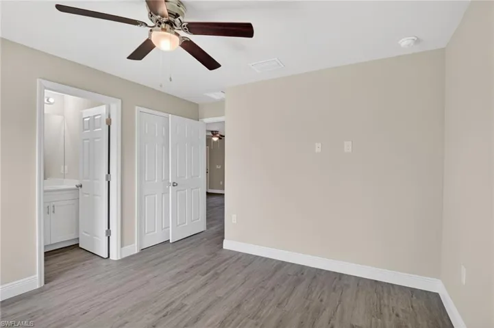 Unfurnished bedroom featuring light wood-type flooring, a ceiling fan, ensuite bathroom, and a closet