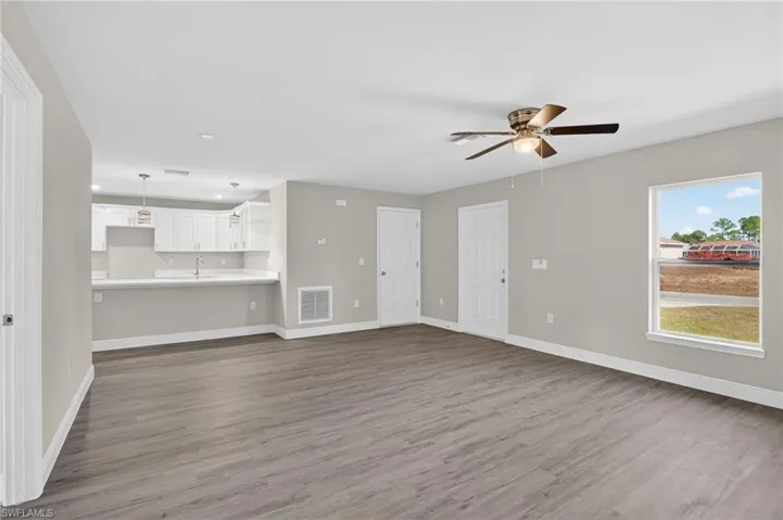 Unfurnished living room featuring dark wood-style flooring, a ceiling fan, and recessed lighting