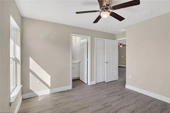 Unfurnished bedroom with light wood-style floors, a ceiling fan, and ensuite bathroom