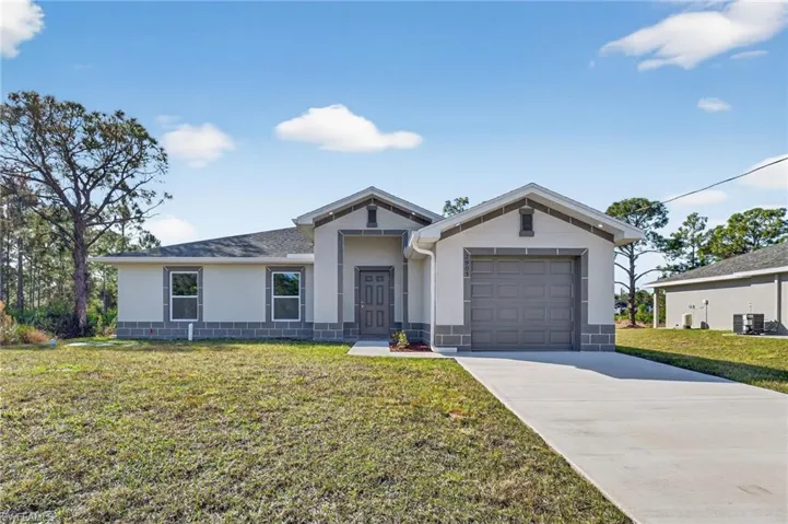 View of front of property featuring stucco siding, a front lawn, driveway, and an attached garage