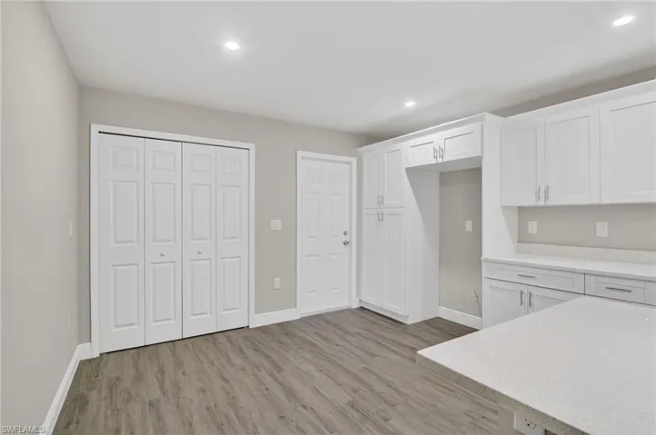 Kitchen featuring white cabinets, light wood-style flooring, light stone counters, and recessed lighting