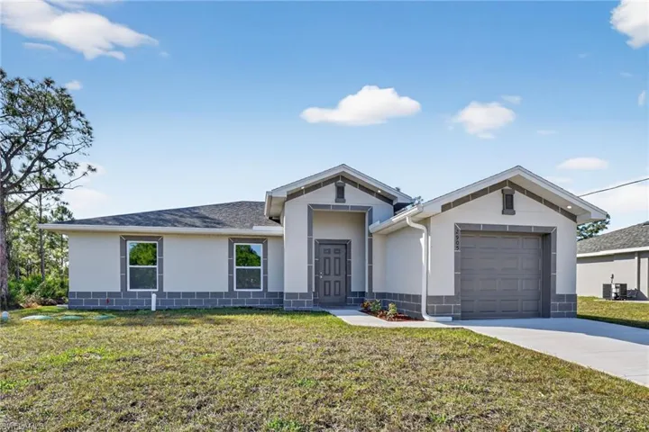 Ranch-style home with stucco siding, a front yard, driveway, and a garage
