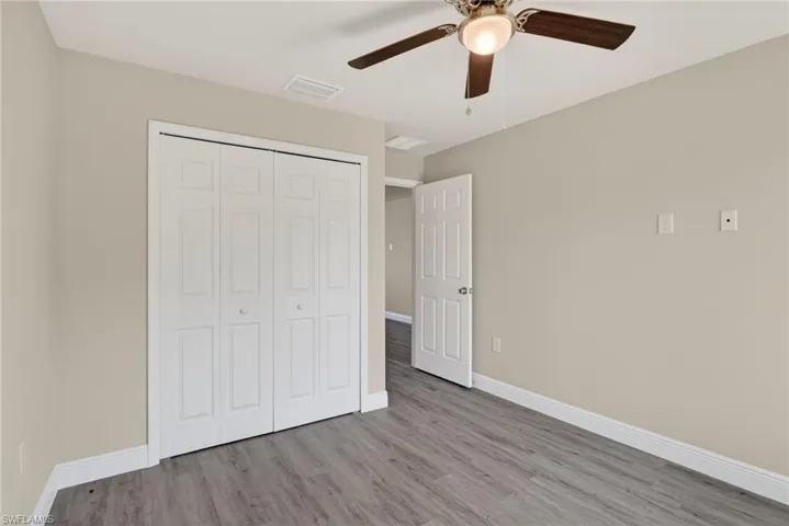 Unfurnished bedroom with light wood-type flooring, ceiling fan, and a closet