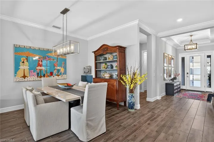 Dining room with a chandelier, wood finish floors, and crown molding