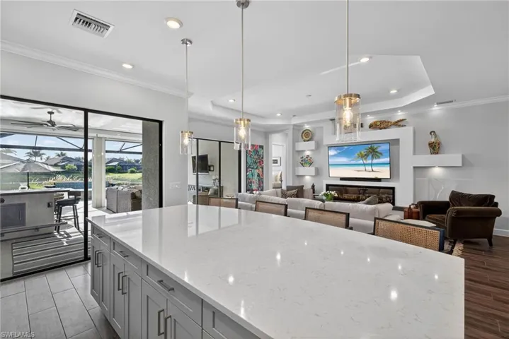 Kitchen featuring a large island, ornamental molding, light stone countertops, open floor plan, and recessed lighting