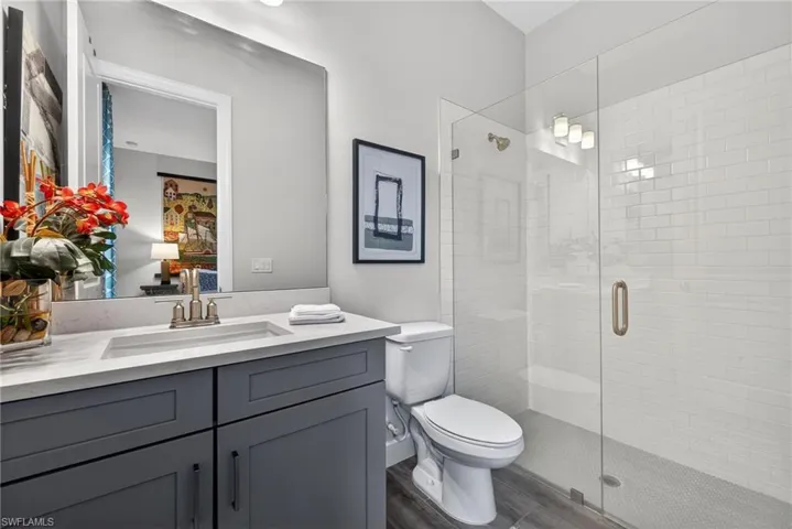 Bathroom with vanity, a shower stall, and dark wood-style floors