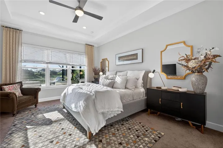 Carpeted bedroom featuring a tray ceiling, ceiling fan, and recessed lighting