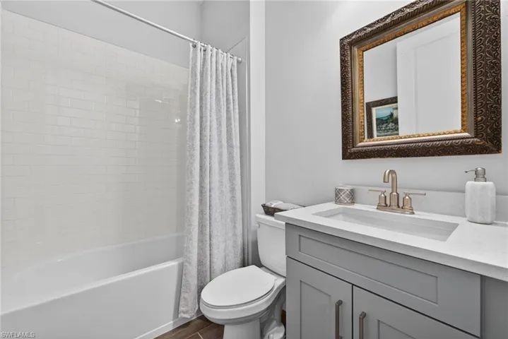Bathroom featuring vanity, shower / tub combo, and dark wood finished floors