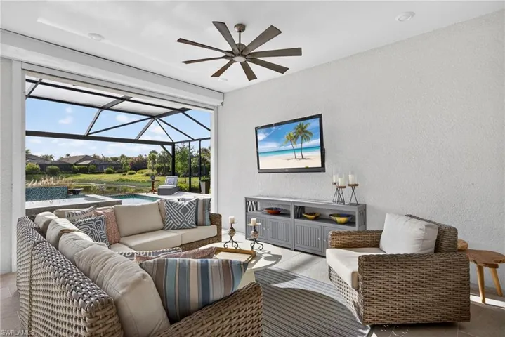 Living area featuring a sunroom, a textured wall, and a ceiling fan