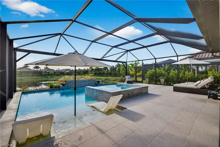 Swimming pool with a sunroom, glass enclosure, a patio, and a hot tub