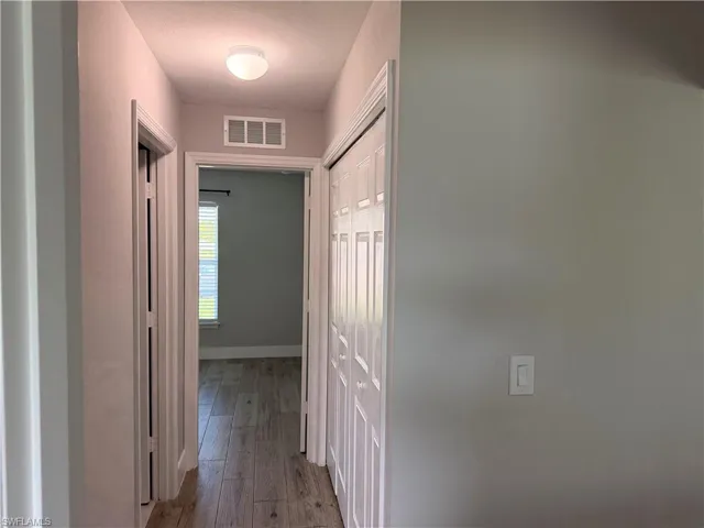 Hallway featuring wood-finish flooring, light gray wall paint, and white trim