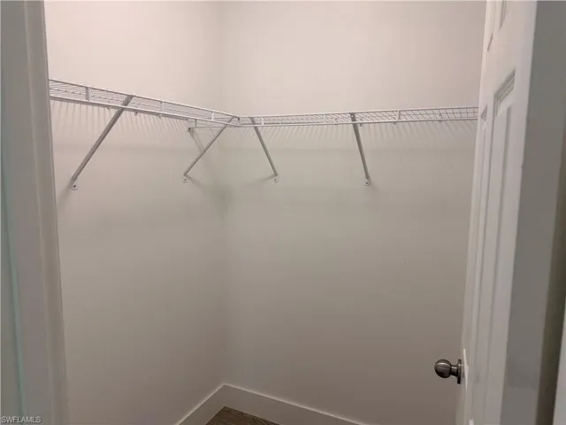 Walk-in closet featuring white wire shelving, light-toned walls, and wood-finish flooring