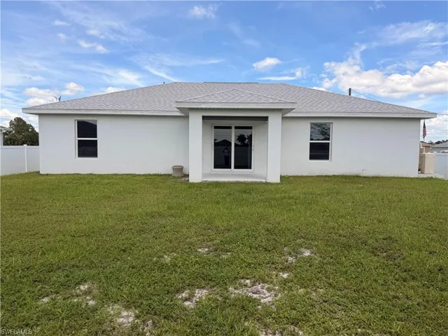 White stucco exterior featuring a grey shingle roof, dual pane windows, and a covered patio with sliding glass doors