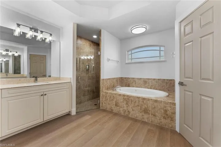 Bathroom with a garden tub, a shower stall, wood finished floors, and vanity