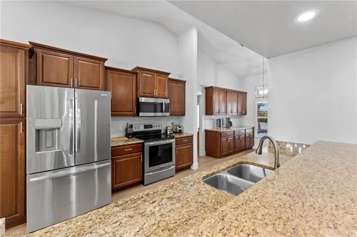 Kitchen with a sink, stainless steel appliances, light wood-style floors, a chandelier, and backsplash