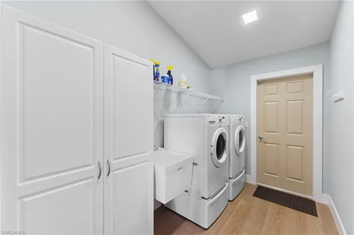 Laundry room featuring baseboards, laundry area, washer and clothes dryer, and light wood-style floors