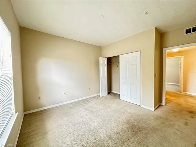 Unfurnished bedroom with light colored carpet and a closet