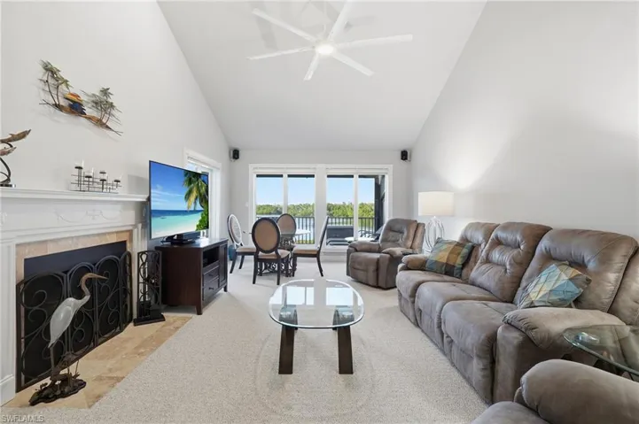 Living room with high vaulted ceiling, a tile fireplace, and a ceiling fan