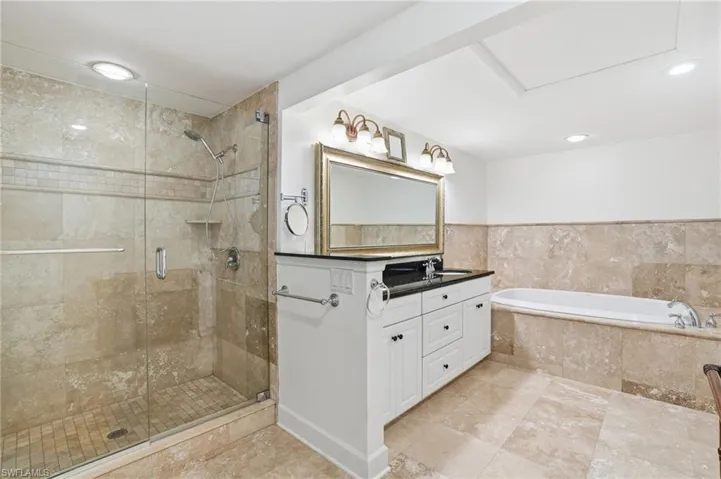 Bathroom with double vanity, a bath, and a shower stall