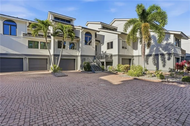 View of building exterior featuring an attached garage, stairs, and driveway