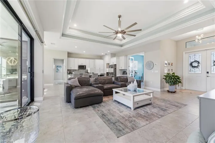 Living room featuring ceiling fan, ornamental molding, recessed lighting, and a raised ceiling