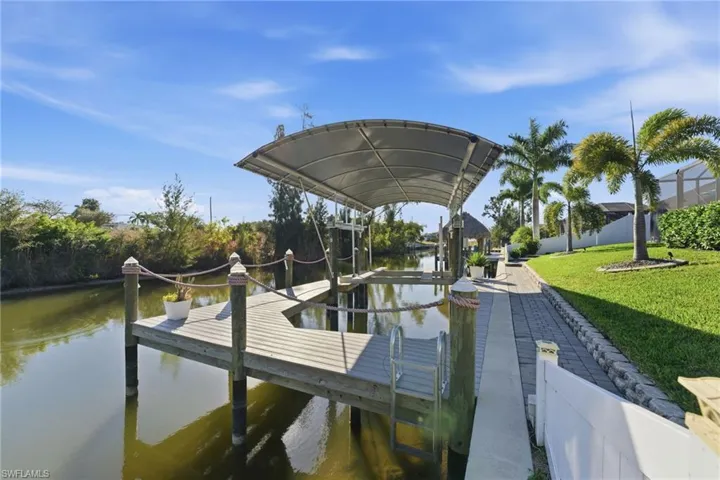 Dock area with a water view, boat lift, and a yard