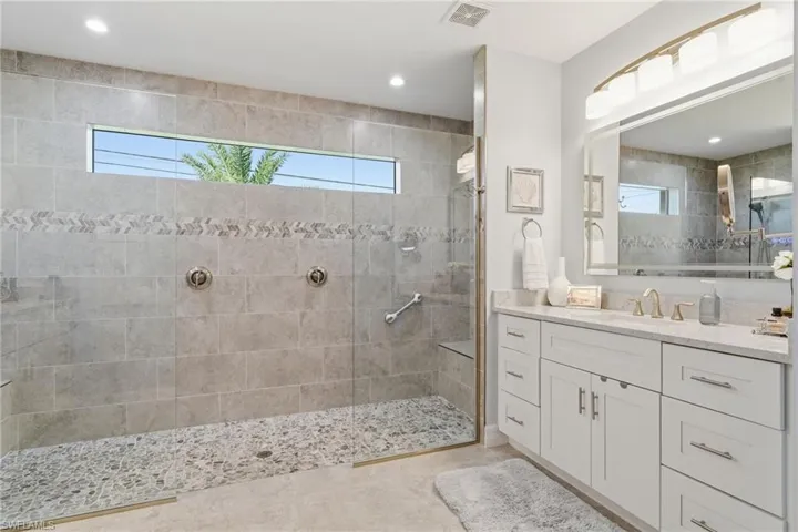 Full bath featuring vanity, walk in shower, and healthy amount of natural light