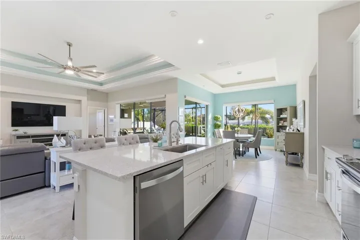 Kitchen with white cabinetry, a raised ceiling, light stone countertops, stainless steel appliances, and a breakfast bar