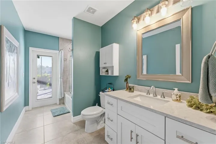 Full bath with vanity, shower / bath combo, and light tile patterned floors