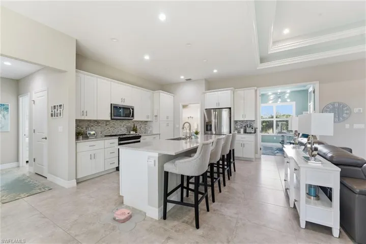Kitchen featuring white cabinetry, a kitchen breakfast bar, an island with sink, backsplash, and recessed lighting
