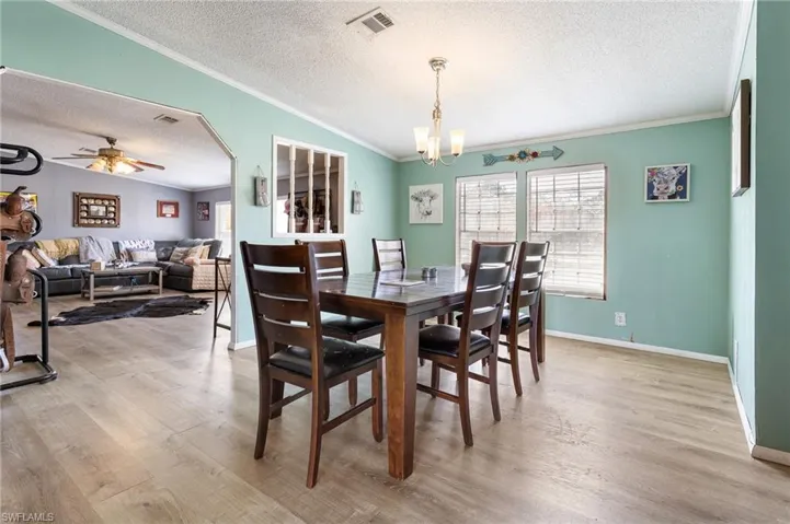 Dining room featuring ceiling fan, ornamental molding, light wood-style flooring, and suspended lighting