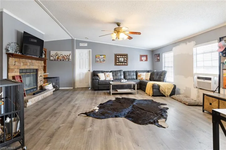 Living area featuring ornamental molding, wood finished floors, ceiling fan, a fireplace, and cooling unit
