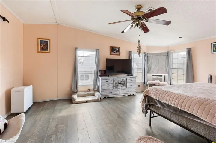 Bedroom with ceiling fan, hardwood / wood-style flooring, crown molding, and cooling unit
