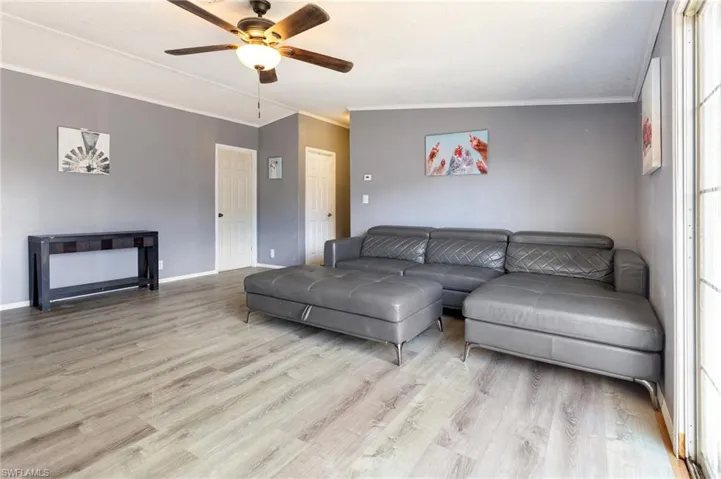 Living area featuring ornamental molding, light wood-style floors, and ceiling fan