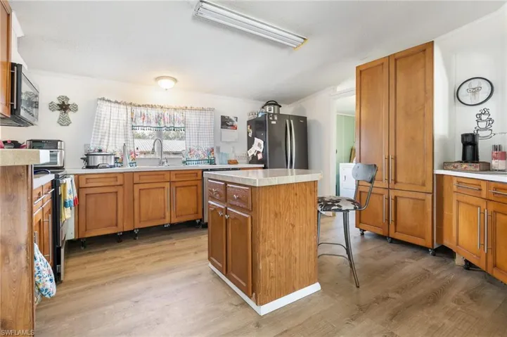 Kitchen with wood finish cabinets, light countertops, a center island, light wood-style floors, and ornamental molding