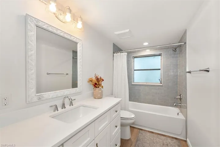 Bathroom with shower / bath combo with shower curtain, vanity, and dark wood finished floors