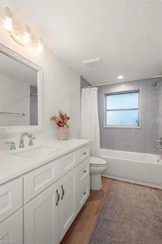 Full bath featuring light wood-style floors, vanity, and shower / bathtub combination with curtain