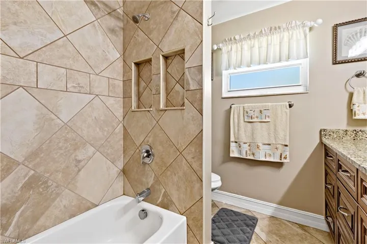 Full bathroom with toilet, tiled shower / bath, vanity, and tile patterned floors