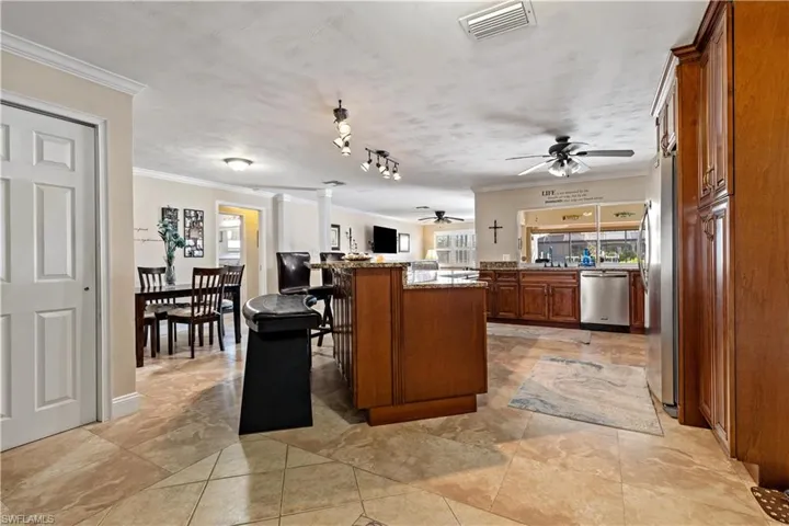 Kitchen featuring appliances with stainless steel finishes, a center island, light stone counters, a kitchen breakfast bar, and crown molding