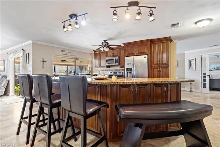 Kitchen with decorative backsplash, ornamental molding, stainless steel appliances, and ceiling fan
