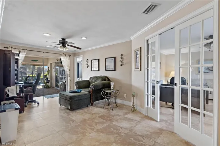 Living room with french doors, ornamental molding, and ceiling fan