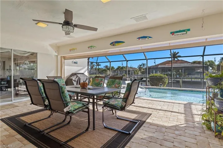 View of swimming pool with a patio, ceiling fan, and glass enclosure