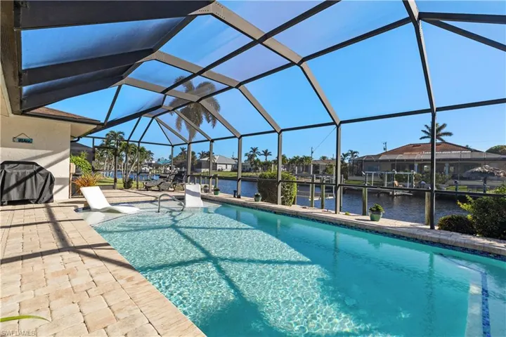 View of swimming pool with a water view, a patio area, and glass enclosure