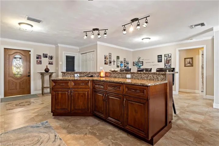 Kitchen featuring ornamental molding, a kitchen breakfast bar, and a center island