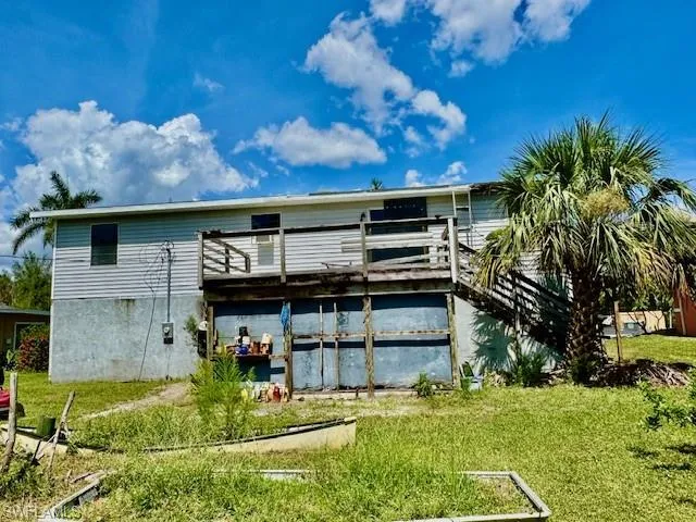 Back of property featuring a lawn and a deck