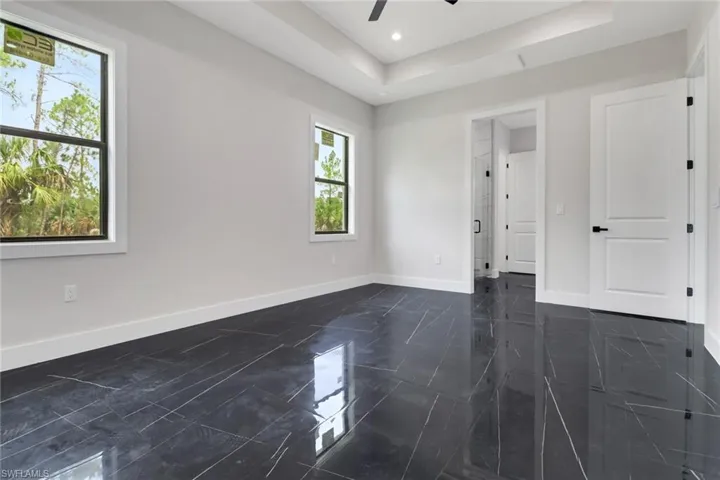 Light and bright primary bedroom with tile flooring and en suite bathroom