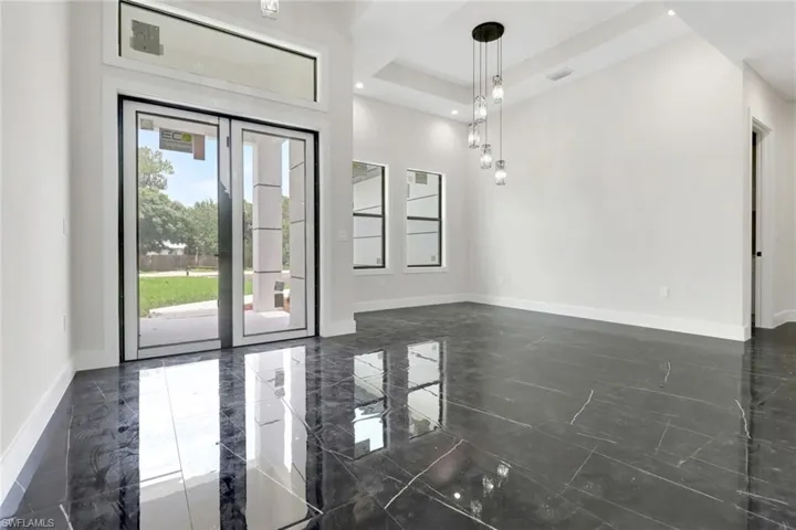 Foyer with glass entry doors and dining area with upgraded modern lighting